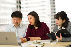 Hirano-Iwata in discussion with her laboratory staff. She finds the research environment at AIMR conducive to cooperative research.